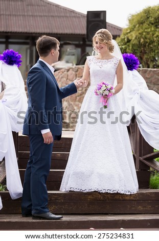 Handsome groom giving hand to smiling bride walking down the stairs