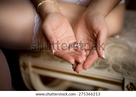 Closeup shot of beautiful bride in lingerie holding wedding rings in hands