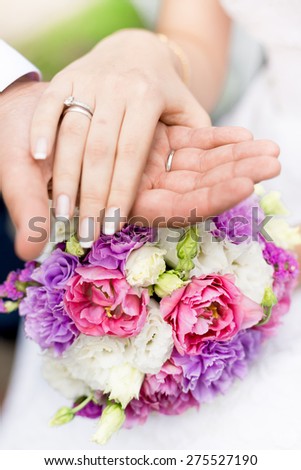 Closeup soft focus photo of groom holding brides hand on bridal bouquet