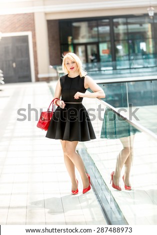 Beautiful elegant woman in short black dress posing in the shopping mall