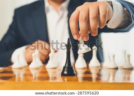 Closeup toned photo of businessman making move with white pawn on chess board