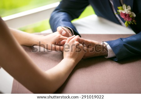 Closeup photo of just married couple holding hands at restaurant