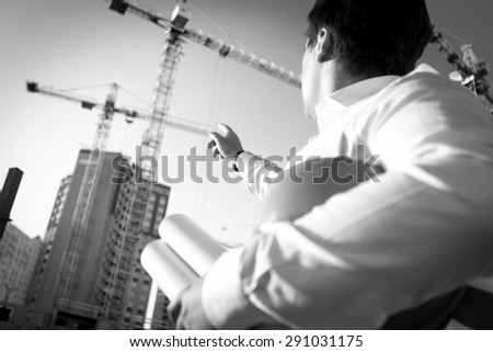 Black and white closeup photo of engineer pointing at the building under construction