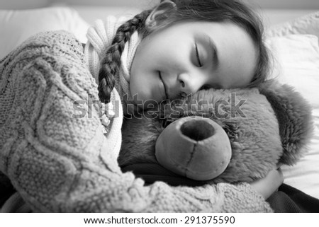Closeup black and white portrait of cute dreaming girl hugging teddy bear