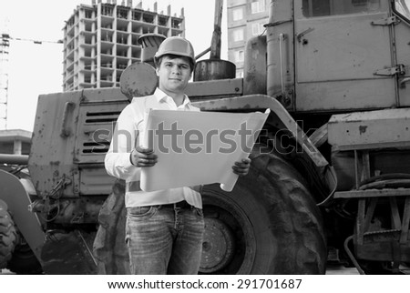 Black and white portrait of engineer reading instructions to bulldozer