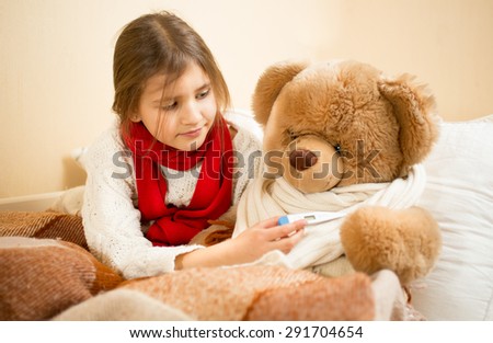 Portrait of little girl playing with teddy bear in doctor and patient