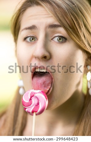 Cute girl with pigtails licking twisted red lollipop