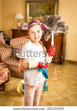 Portrait of smiling girl doing cleaning posing with feather brush