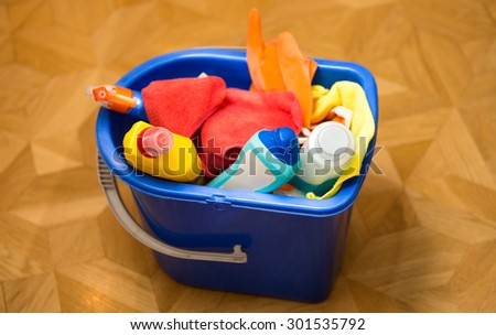 Closeup photo of plastic bucket with cleaning equipment standing on floor