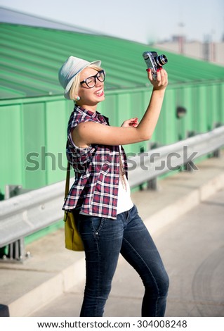 Happy hipster girl in hat making picture on vintage camera