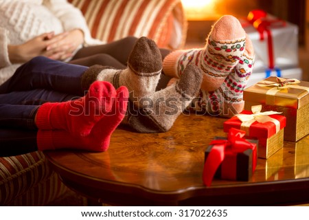 Closeup photo of family\'s legs in woolen socks next to fireplace at Christmas