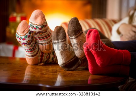 Closeup photo of family feet in wool socks at fireplace