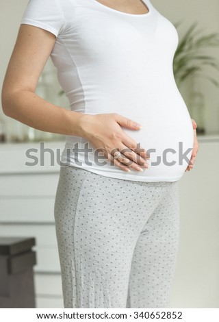 Beautiful pregnant woman in white t-shirt touching big belly