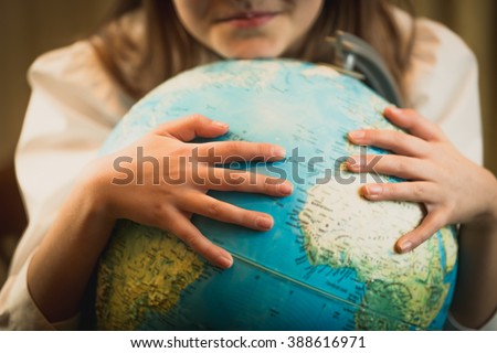 Closeup image of cute girl holding hands on Earth globe. Concept of environment protection