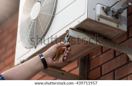 Closeup photo of male technician installing outdoor air conditioning unit