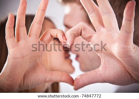 Young couple is kissing  and making heart from their fingers