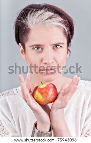 Young caucasian fashion model holding apple and smiling