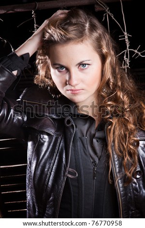 Beautiful young lady with curly hair posing in black leather coat