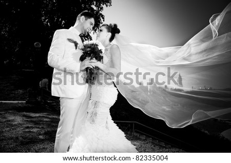 black and white portrait of newly married couple.wind lifting up long veil