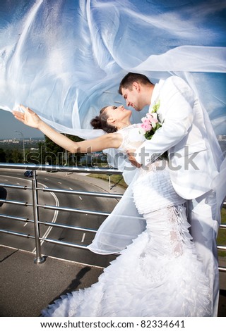 Young caucasian newly married couple covered with long white veil