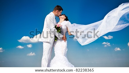 newly married couple.wind lifting long white bridal veil