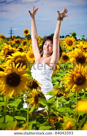 Young beautiful girl in white dress jumping high in yellow flower field