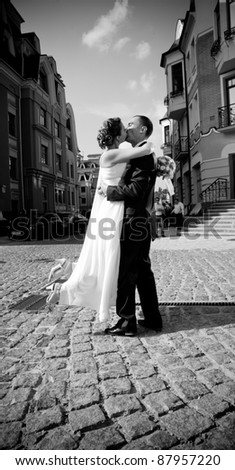 Black and white photo of young newly married couple kissing outdoor