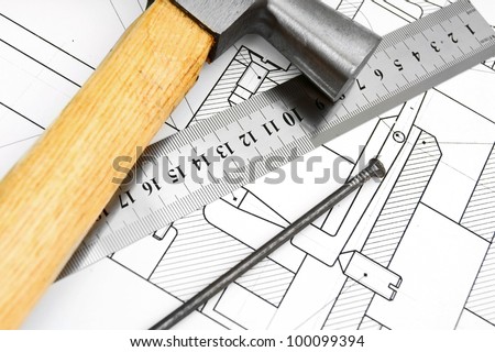 Hammer, ruler and nail on the drawing.
