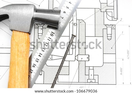 Hammer, ruler and nail on the drawing.