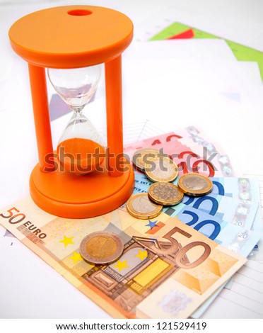 Sand-glass, coins and euro on graphs.