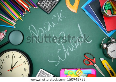 Back to school. Watch, an alarm clock and school accessories on a school board.
