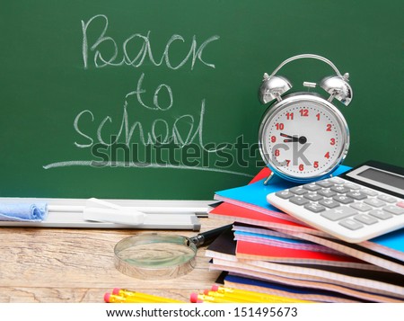 Back to school. An alarm clock and other school accessories against a school board.