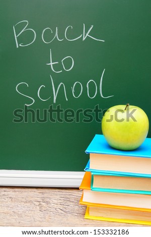 Back to school. An apple on books against a school board.
