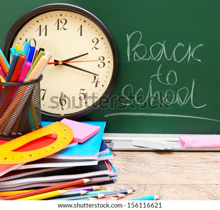 Back to school. Watch and school accessories against a school board.