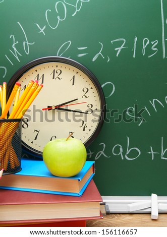 Back to school. Watch, an apple and school subjects against a school board.