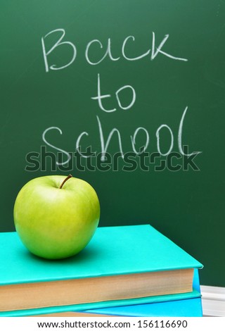 Back to school. An apple and books against a school board.