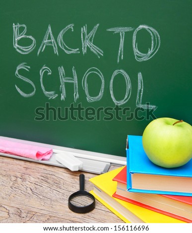 Back to school. An apple on books against a school board.