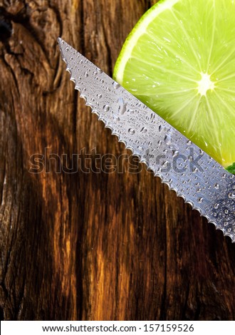 Lime and knife. On a wooden board.