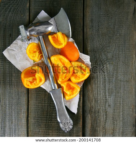Hammer in the squeezed out segments of oranges. On a wooden background.