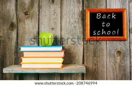 Back to school. An apple and books on a wooden shelf.