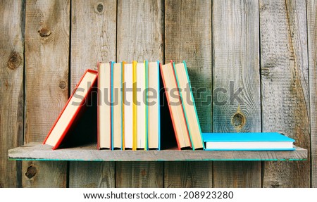 Books on a wooden shelf. On a wooden background.