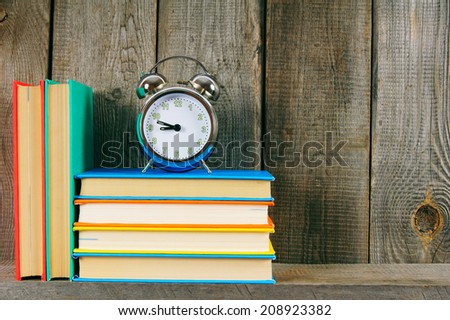 Alarm clock and books. On a wooden background.