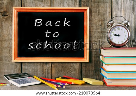 Back to school. An alarm clock, books and other school accessories. On a wooden background.