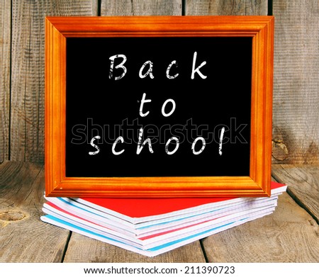 Back to school. Frame and writing-books. On a wooden background.