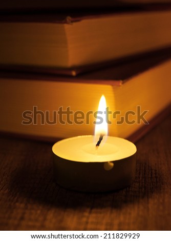 Books and candle. On a wooden background.