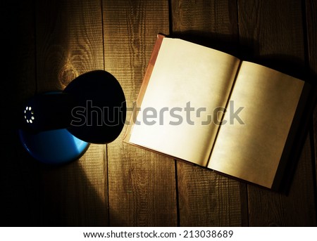 The open book and the fixture. On a wooden background.