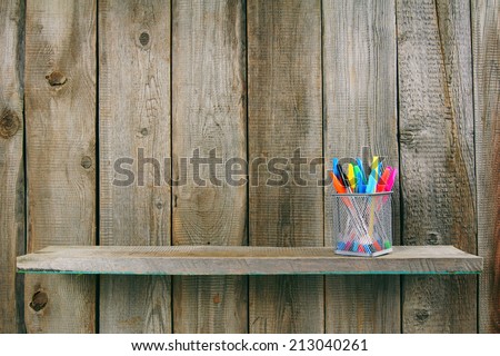 Pens on a wooden shelf. On a wooden background.