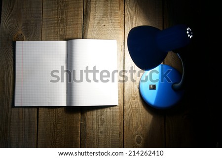 Open writing-book and the fixture. On a wooden background.