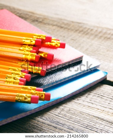 Pencils and writing-books. On a wooden background.