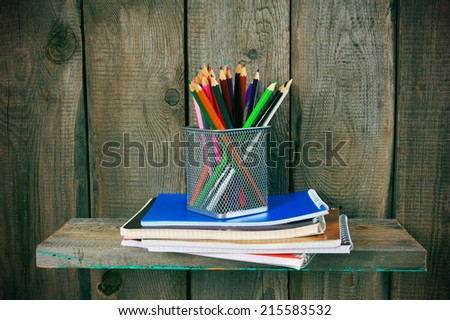Writing-books and school tools on a wooden shelf. On a wooden background.